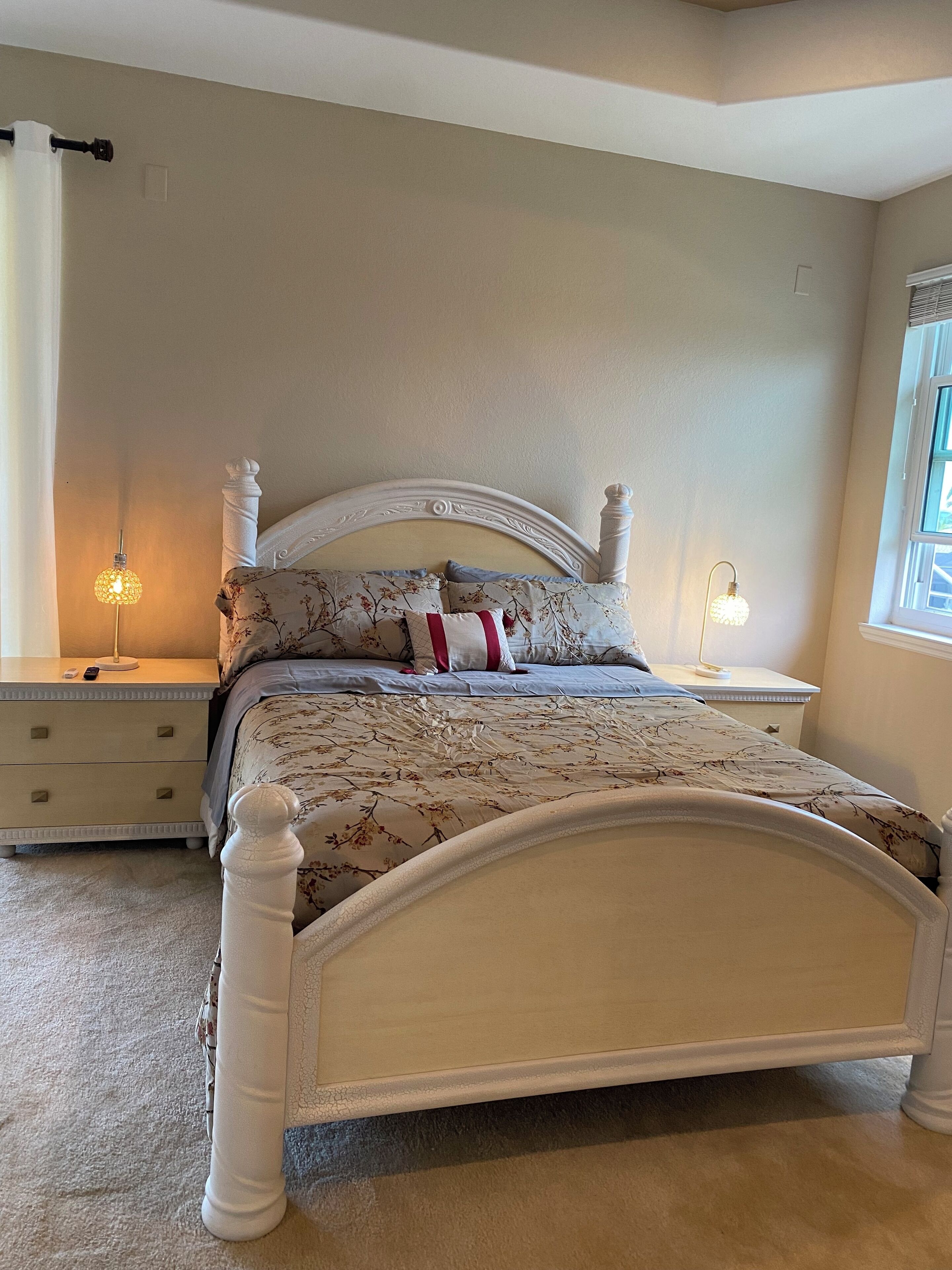 A bedroom with a bed, nightstands, and a window.