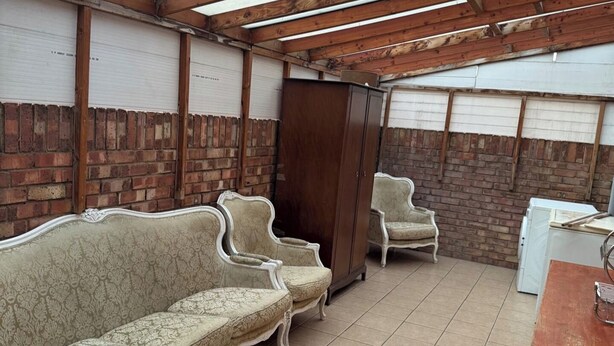 A room with a wooden ceiling, brick walls, a sofa, a cabinet, and a small table. - 2 bed-Sleeps 4-Private Patio-Pets-Near Heathrow (Hounslow)
