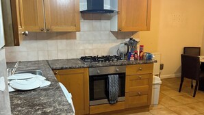 A compact kitchen with wooden cabinets, a gas stove, a built-in oven, and a small countertop. - 2 bed-Sleeps 4-Private Patio-Pets-Near Heathrow (Hounslow)
