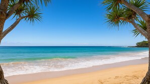 A beach with clear turquoise water, sandy shore, and palm trees framing the view. - 500m to Beach- Large Balcony and Yard | Pet Friend (Ocean Grove)