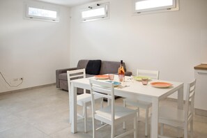 A dining area with a white table and chairs, a sofa, and a bottle of wine. - Dimora Cristal With Pool And Padel, Galatina, Italy (Galatina)