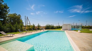 Una piscina rectangular con agua cristalina y azul, rodeada por una solana con baldosas.