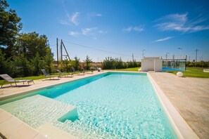 A rectangular swimming pool with clear blue water, surrounded by a tiled deck.