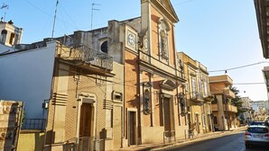 Un edificio histórico con una torre de reloj, un balcón y una estatua.