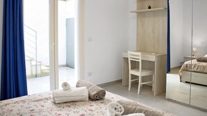 Un dormitorio con cama, escritorio, silla, espejo y baño.