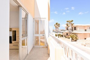 A balcony with a view of palm trees and a building in the background.