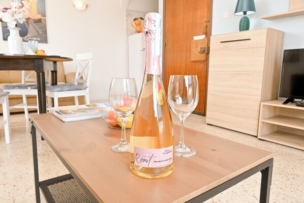 Eine Flasche Rosat Prosecco DOC Gavi auf einem Holztisch mit zwei leeren Weingläsern.
