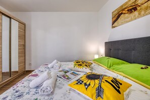 A bedroom with a bed, pillows, a magazine, and a painting on the wall. - Island Top Sea View Terrace Apartment, Veli Lošinj, Croatia (Veli Lošinj)
