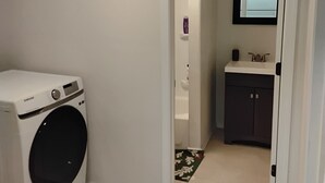 A laundry room with a Samsung washer and dryer, a small sink, and a mirror above the sink. - Cozy Hideaway Parks + Trails Near SLC Airport (Lake Point)