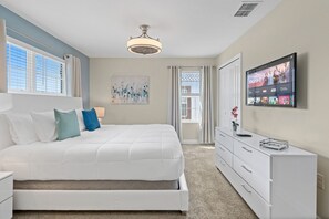 Quarto com cama, televisão, penteadeira e janela.