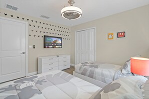 A bedroom with two beds, a TV mounted on the wall, and a dresser.