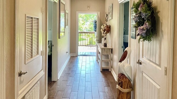 A hallway with a tiled floor, white doors, and a ceiling light.