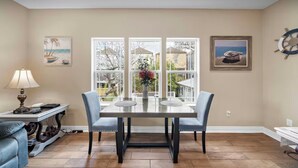 A dining area with a table and chairs, a lamp, and artwork on the walls.