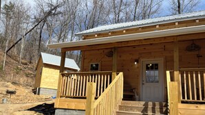 A wooden cabin with a porch, a front door, and a staircase leading to the entrance.
