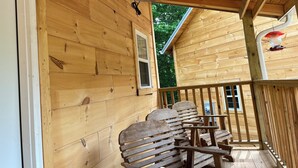A wooden cabin with a porch featuring a bench and a hanging light fixture.