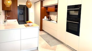 Een moderne keuken met witte kasten, een zwarte oven en twee hanglampen.