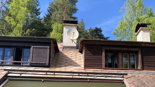 A rustic building with a stone patio, wooden furniture, and a satellite dish. - Gallys Mounting Cottage Pod Boubinem with WiFi (Lenora)