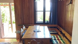 A wooden interior with a large dining table, benches, and a glass table lamp. - Gallys Mounting Cottage Pod Boubinem with WiFi (Lenora)