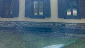 A building with a sloped roof, multiple windows with shutters, and a stone base. - Gallys Mounting Cottage Pod Boubinem with WiFi (Lenora)