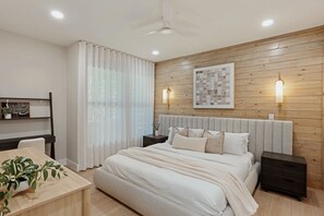 Une chambre à coucher moderne avec une tête de lit en bois, un grand lit, des tables de chevet, un bureau et une chaise.