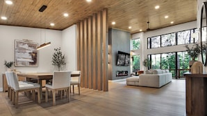 Un vaste espace de vie doté d’un plancher en bois, d’une table à manger avec des chaises, d’un canapé et d’un téléviseur fixé au mur.