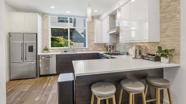A modern kitchen with a large island, stainless steel appliances, and a view of the outdoors. - Perch - Walk to Space Needle | 3BR/2BA Home w Parking! (Seattle)
