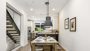 A modern kitchen with a dining area, featuring a staircase, a large window, and a pendant light. - Perch - Walk to Space Needle | 3BR/2BA Home w Parking! (Seattle)