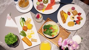 A breakfast setting with plates of food, a cup of coffee, and a bowl of soup.