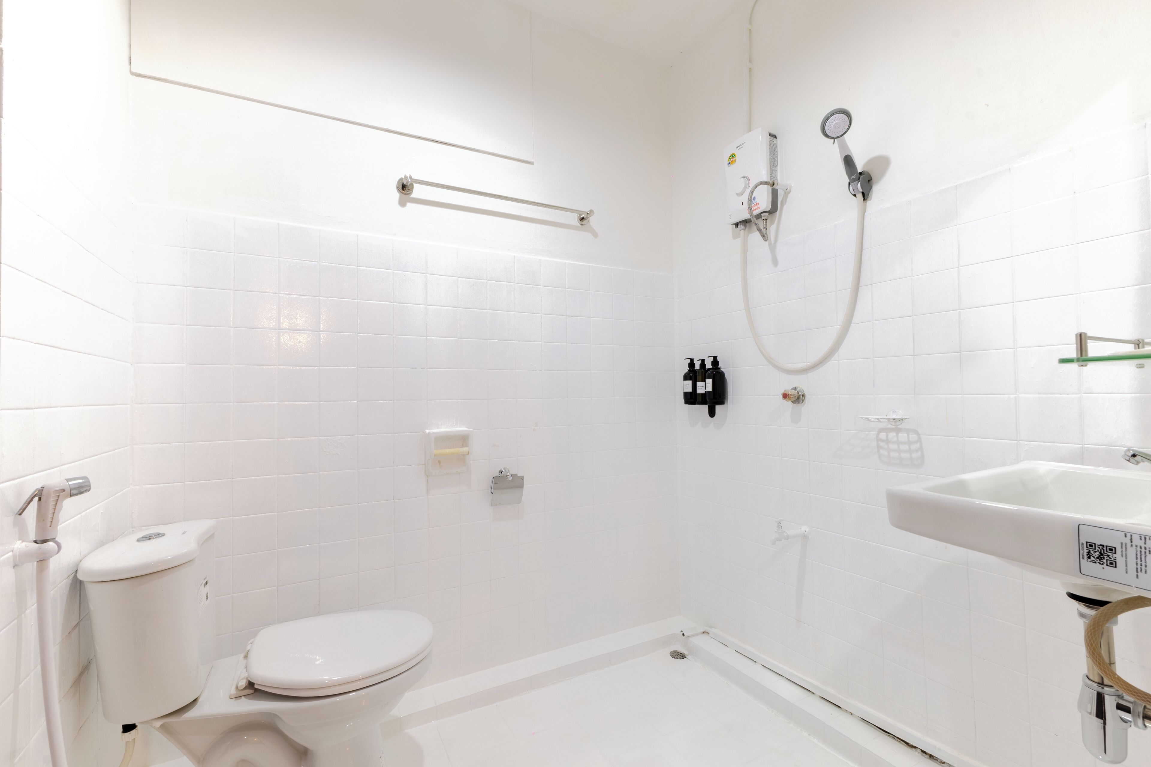 A white bathroom with a toilet, a shower, and a sink.