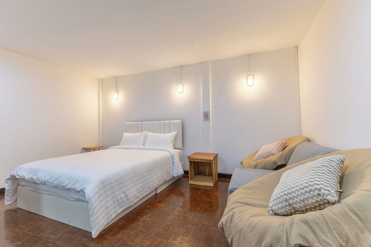 A bedroom with a large bed, a smaller bed, and a nightstand with a lamp.