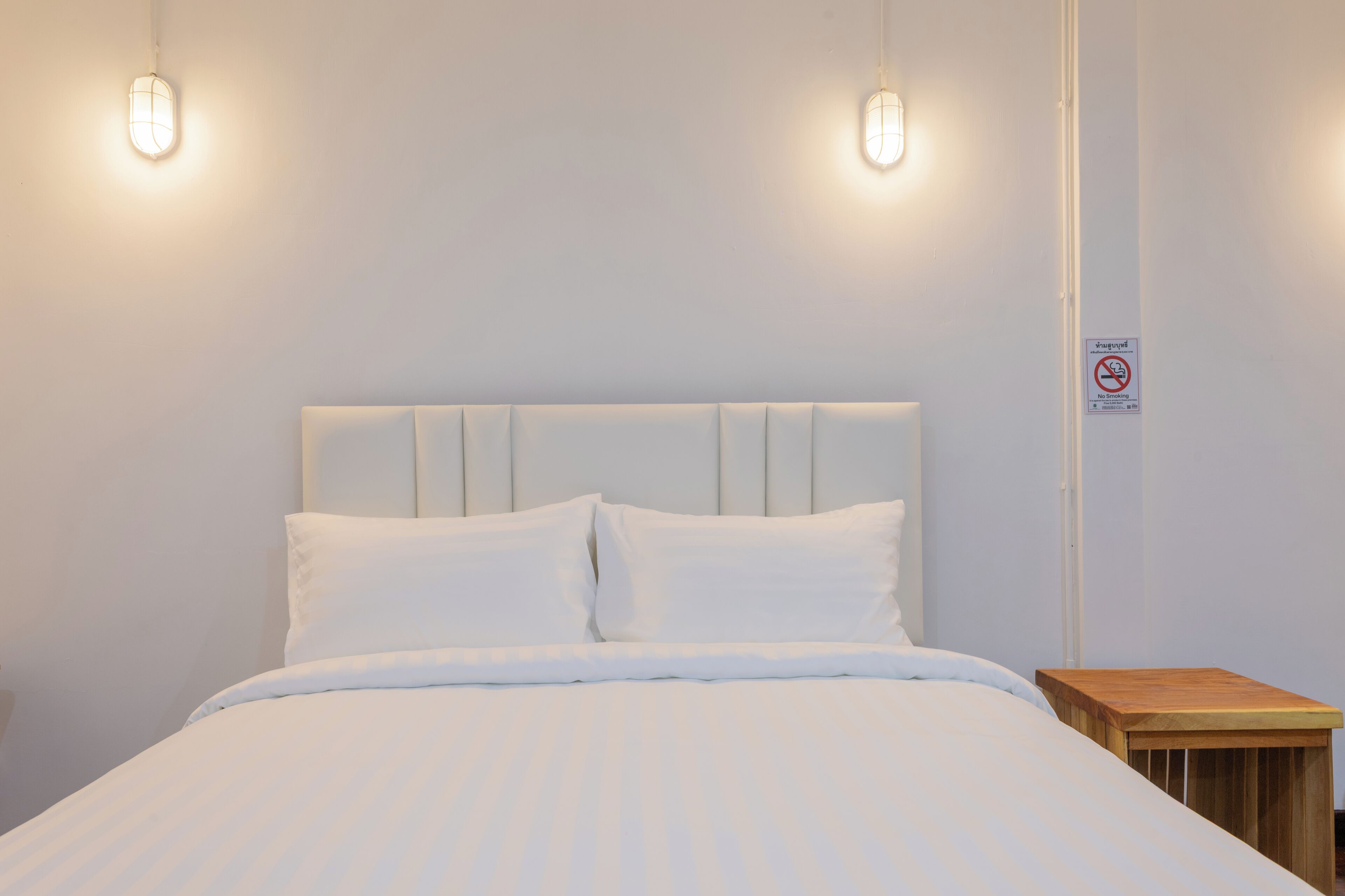 A neatly made bed with a white headboard and two bedside lamps.