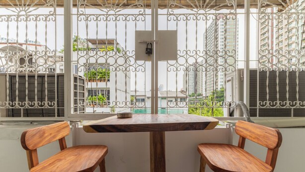 Een balkon met een houten tafel en twee stoelen, met uitzicht op een stadsgezicht met wolkenkrabbers.
