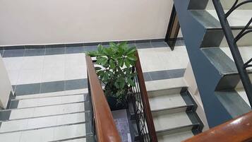 Una escalera con una planta en maceta, señales direccionales para el Restaurante Hyray y la Sala de Juntas Flax, y un cartel que indica la habitación 10-104.