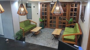 Un espace de détente moderne avec un canapé vert, une table basse en bois et des lampes suspendues.