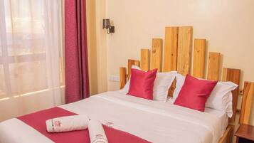 A hotel room with a wooden headboard, white bedding, and red accents.