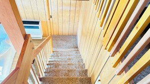 A wooden staircase with a handrail and carpeted steps leading to a higher level.