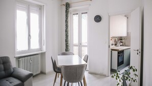A modern kitchen with a built-in oven, a dining area with a white table and chairs, and a radiator. - GuestHost - Borgo Filadelfia Apartment (Turin)