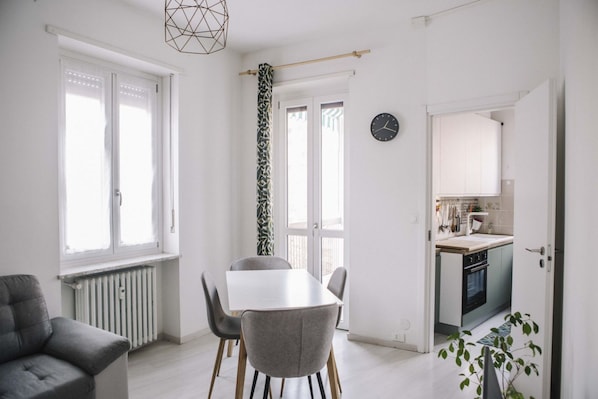 A modern kitchen with a built-in oven, a dining area with a white table and chairs, and a radiator.