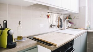 A kitchen with a wooden countertop, a sink, and a hanging utensil rack. - GuestHost - Borgo Filadelfia Apartment (Turin)
