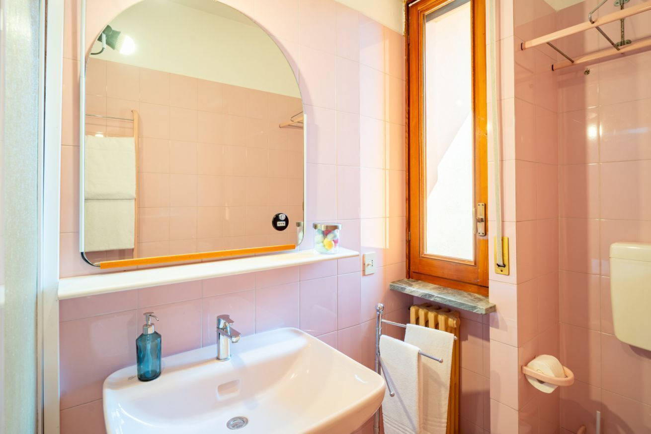 Une salle de bain équipée d’un lavabo, d’un miroir, d’un porte-serviettes et d’une zone douche.