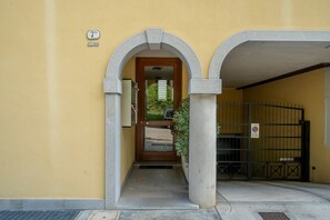 Une entrée d’immeuble avec un panneau indiquant le numéro, une porte et un portail.