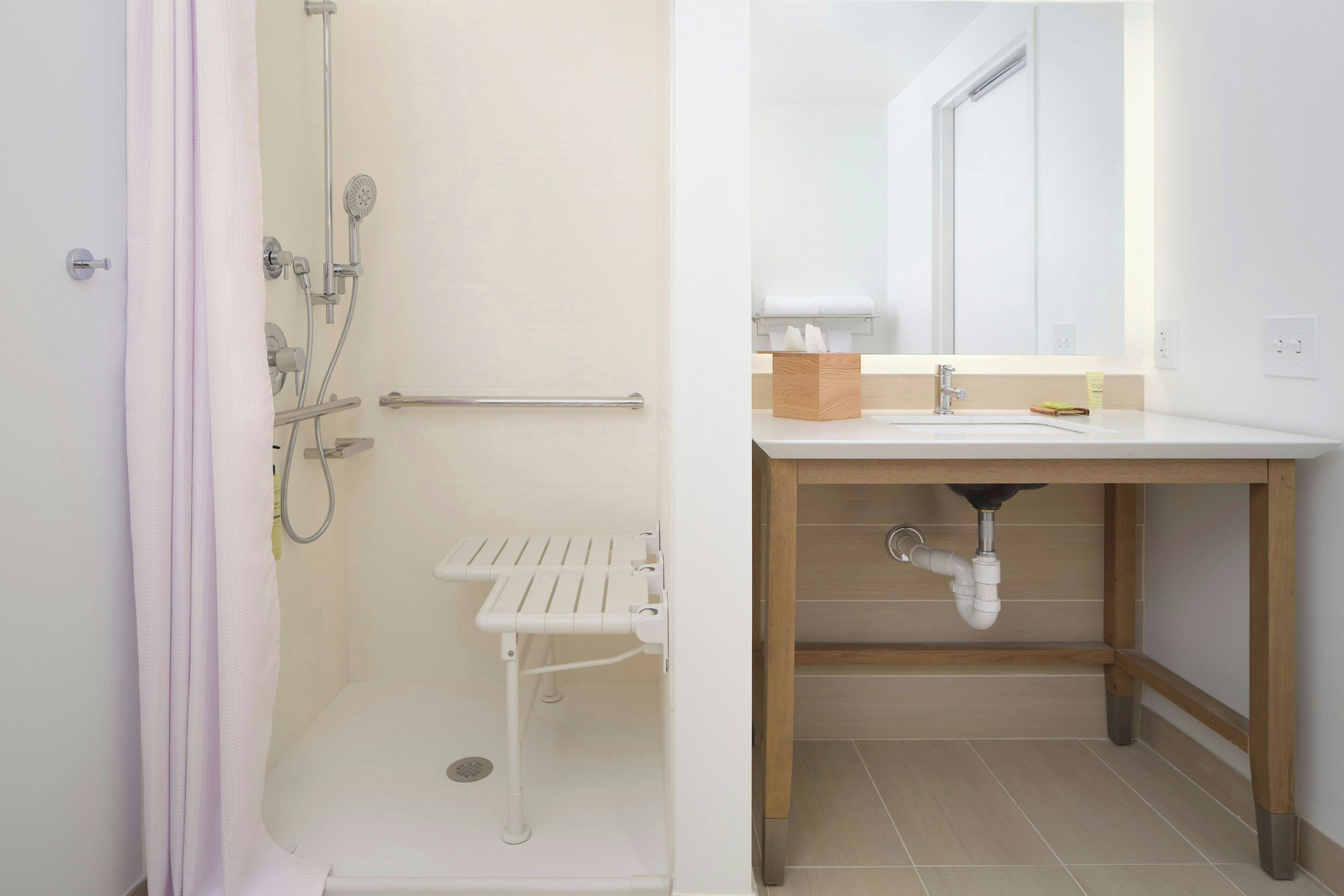 A bathroom with a shower, a sink, and a mirror.
