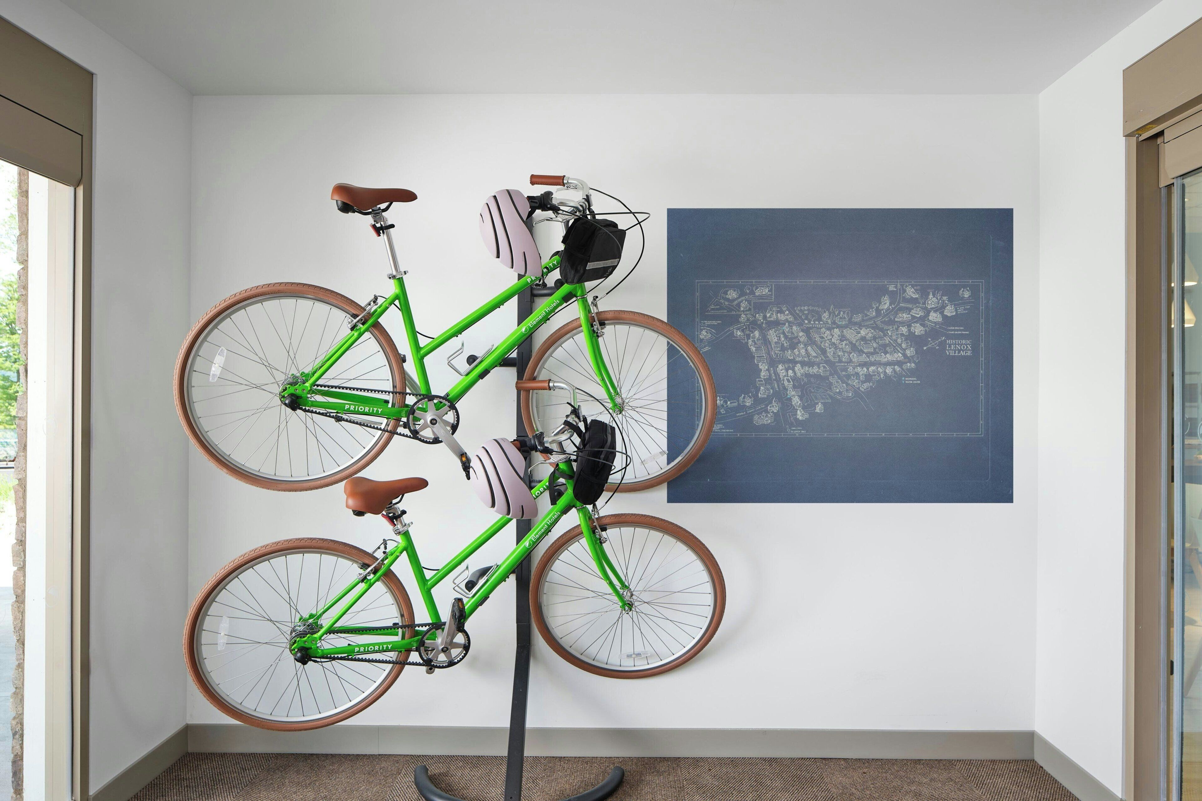A room with a green bicycle mounted on a stand, a map on the wall, and a window providing natural light.