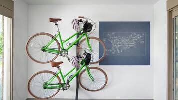 A room with a green bicycle mounted on a stand, a map on the wall, and a window providing natural light.