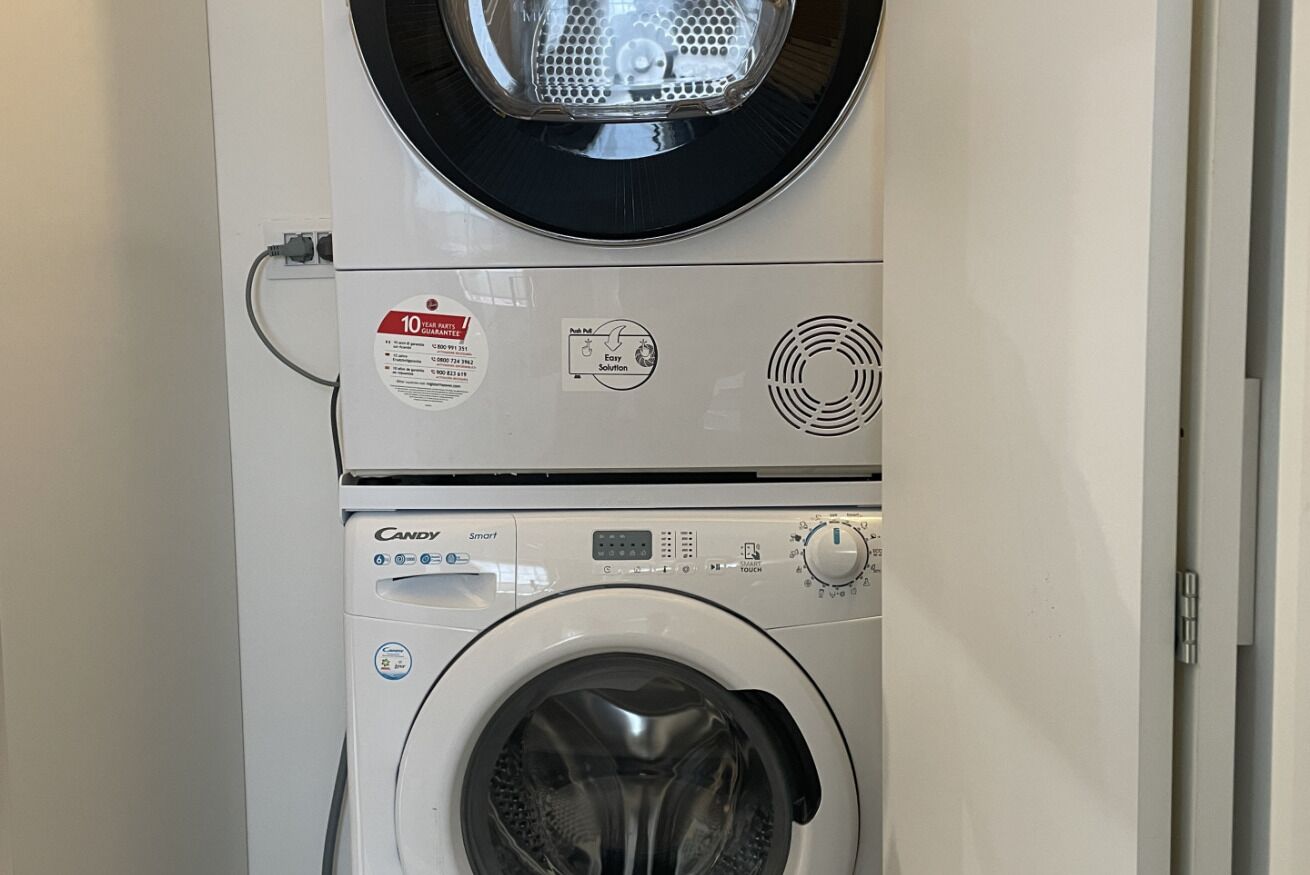 A front view of a stacked washer and dryer unit with a 10-year parts guarantee label, a touch control panel, and a circular vent on the dryer.