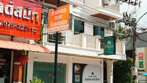 A hotel with a balcony on the second floor, a sign for Place Hotel, and several parked motorcycles in front. - PLACE HOTEL (Karon)