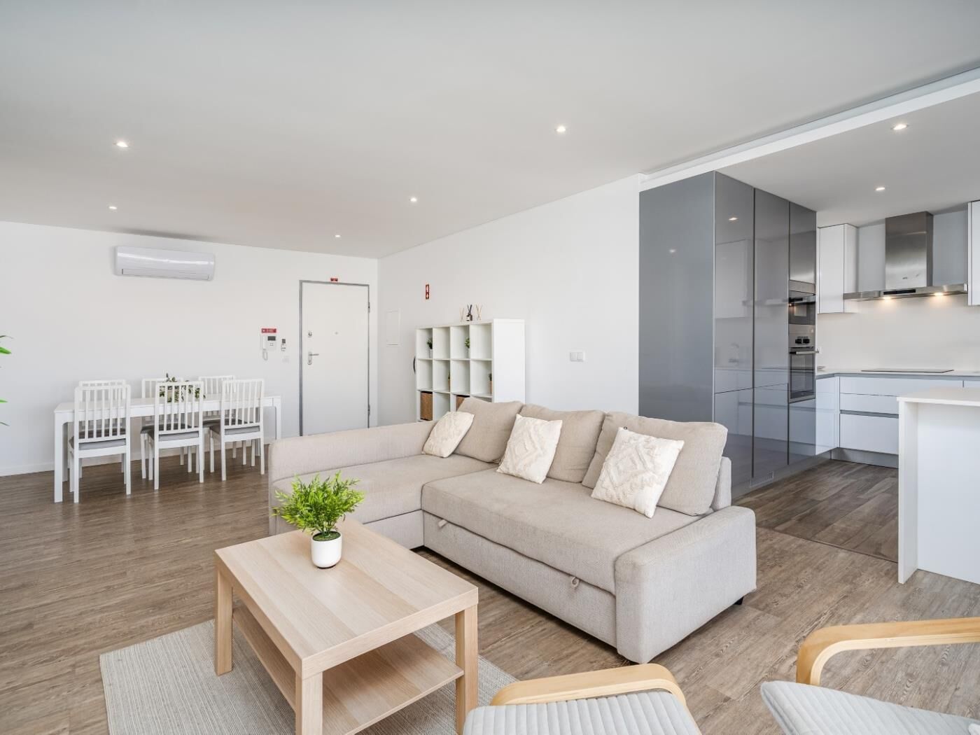 A modern living room with a sofa, a coffee table, and a dining area with chairs.