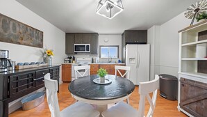 A modern kitchen with a round dining table, white chairs, a built-in oven, microwave, and a refrigerator. - Ample Parking, Farm Experience, Pet-Friendly Home (Kennewick)