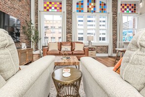Una sala de estar acogedora con un sofá de cuero marrón, dos sillones blancos y una mesa de centro de madera.