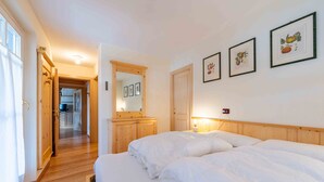 Une chambre à coucher avec un lit en bois, une table de chevet, un miroir et des tableaux encadrés accrochés au mur.